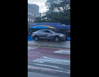 Gray car stuck on road median barricade