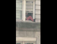 Man sits at edge of apartment window