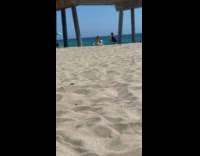 Woman beach hat throws sand under bridge
