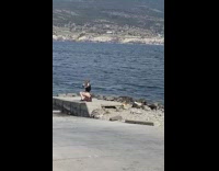 Woman in black outfit poses on the beach rocks