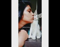 Girl kisses grey white kitten licks face 