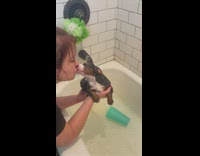 Woman gives dog in bathtub kiss 