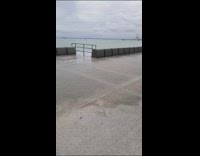 Ocean waves come up the barrier fence