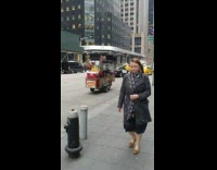 Hot dog man rolls his cart down the street as cars drive by