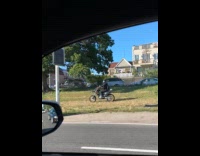 Man drive motorcycle on grass shoulder of road