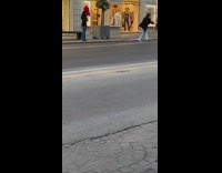 Woman in green trench coat walks in the middle of the road