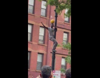 Guy balances ball on head while twerking on streetlamp 