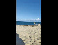 Woman in blue bikini hits by the beach wave