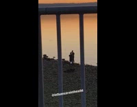 Man beach sunset white shoes metal fence