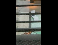 Woman in orange swimsuit dips head in pool while its raining 