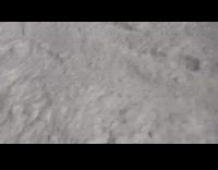 Snowboarder back flips off ramp, hits  tip of snowboard on slope, flips and slams into snow