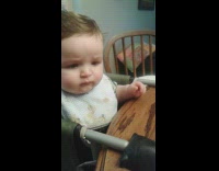 Baby eats baby food with a facial reaction