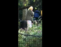 Man green jacket shakes body and arms in front of him in the park 