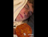 Guy feeds friend sleeping on couch salami 