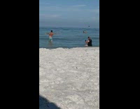 Man shirtless flexes back muscles at the beach