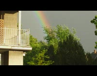 Double rainbow on the cloudy day while rain pours