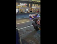 Grinch wearing santa suit drives white car 