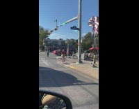 Woman in brown bikini poses beside the stoplight post on the sidewalk