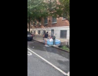 Kids in an inflatable pool beside open fire hydrant