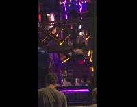 Black shirt lady swings bar purple lights 