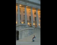 White shirt red vest girl sits steps