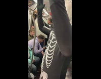 Woman in halloween suit with friends in skeleton costume on subway train