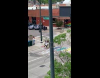 Two ladies in matching outfits walk down rainbow crosswalk 