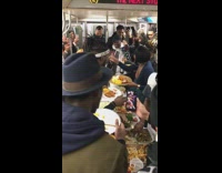 Subway passengers dance and sing together while eating thanksgiving dinner on subway train