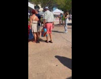 Woman with smoothie poses outside vegetable market