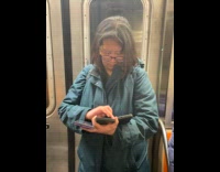 Woman standing on subway uses three phones