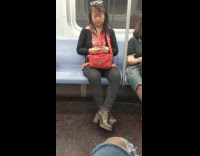 Woman in red floral shirt  clips her fingernails on the subway