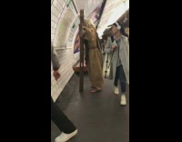 Man dressed up as Jesus holds giant crucifix cross in subway station