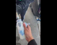 Person bottle feeding his car with gasoline inside