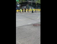 Crowd of People Walk Wearing Yellow Shirts 