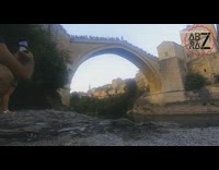 Crowd watches guy jump off bridge water 