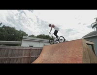 BMX biker does fakie frontflip on brown ramp and cheers with his friend
