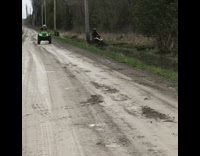 ATV drives through mud next to road 