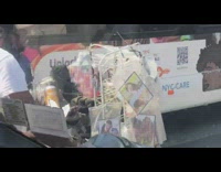 Guy bikes with stuff on handle bars