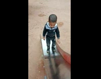 Young boy try to climb up slide