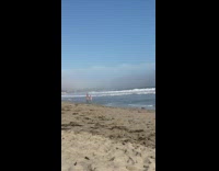 Woman in red bikini walks by the beach shore
