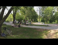 Skater ollies off ramp, lands in grass and falls down on back 