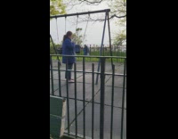 Woman in blue jacket pushing empty swing seat at park