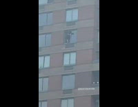 Guy side of apartment building cleans window 