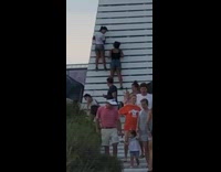 Two girls climb white pavilion beach stairs