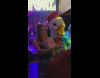 Woman with a drink dances with the chicken mascot