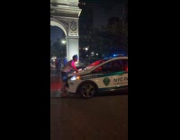 Shirtless man block police car park night