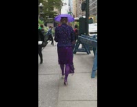 Woman in purple outfit walks down street