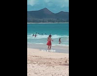 Woman in red dress tiktok dance at the beach