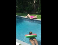 Woman lays next to pool friend takes picture