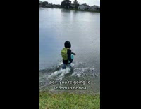 Kid walks into lake with backpack 